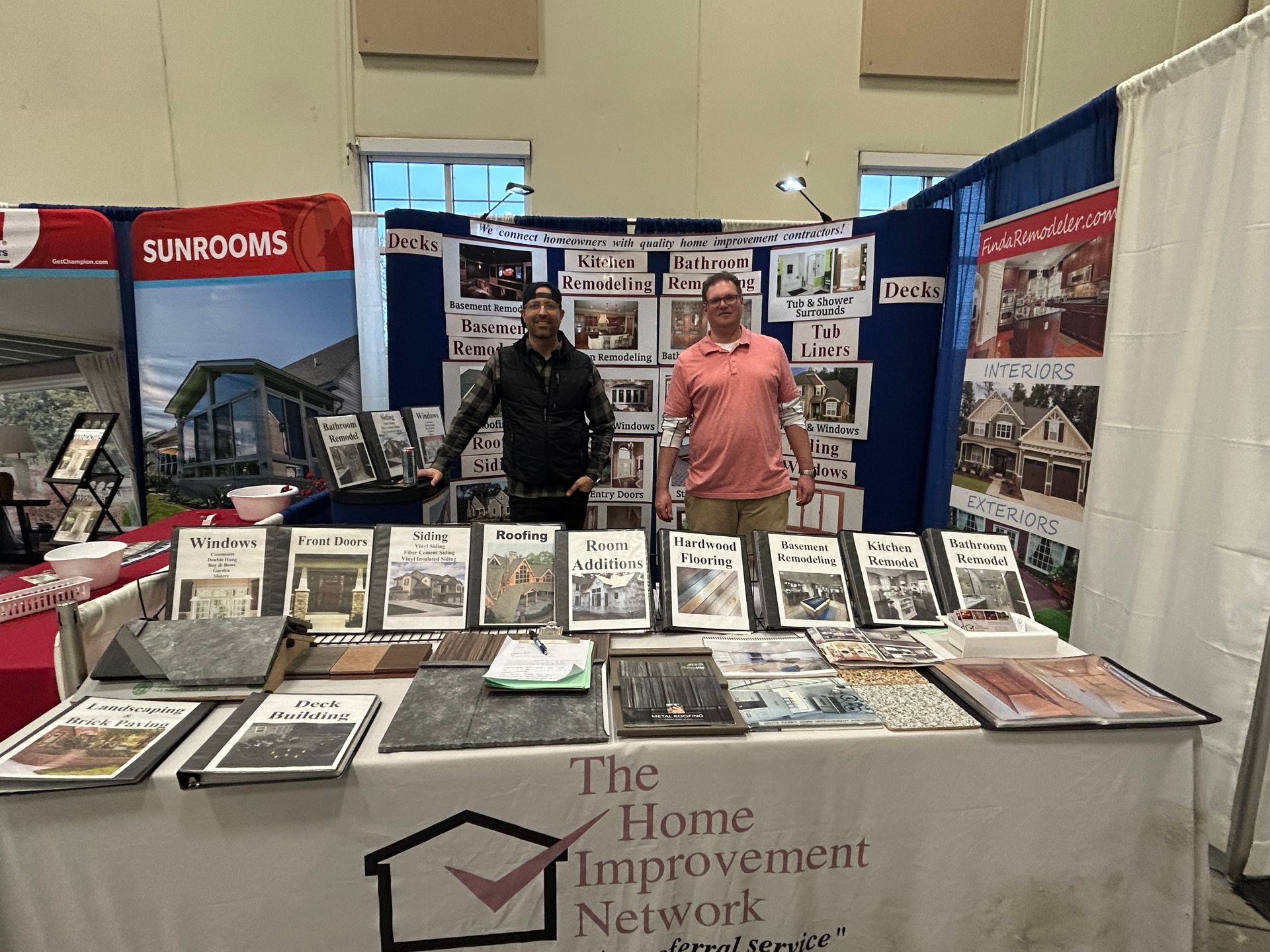 Two men are standing behind a table that says the home improvement network.