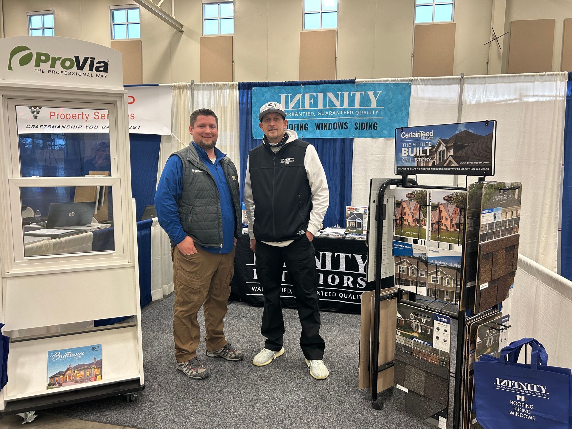 Two men are standing in front of a booth at a convention.