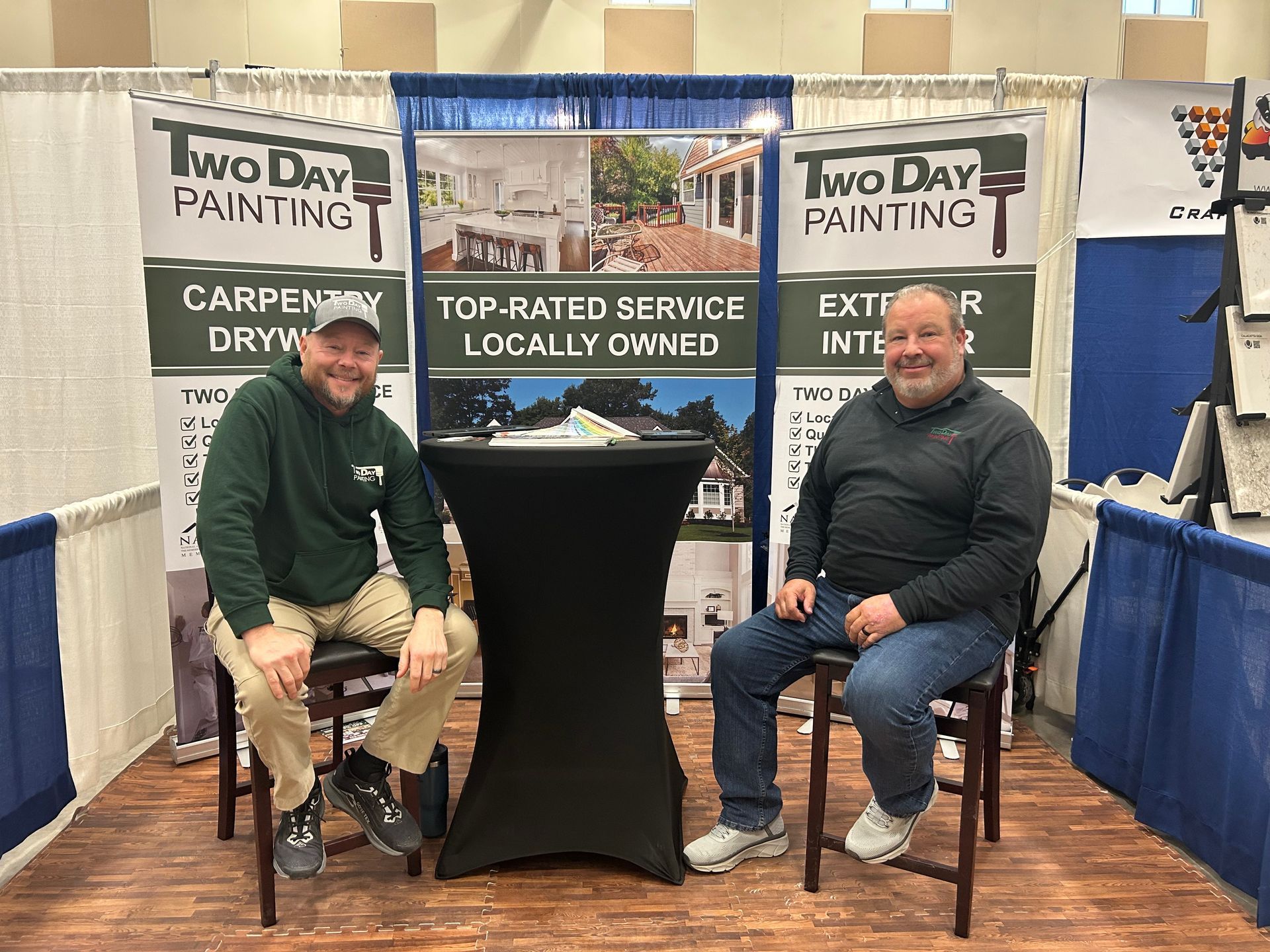 Two men are sitting in front of a two day painting booth.