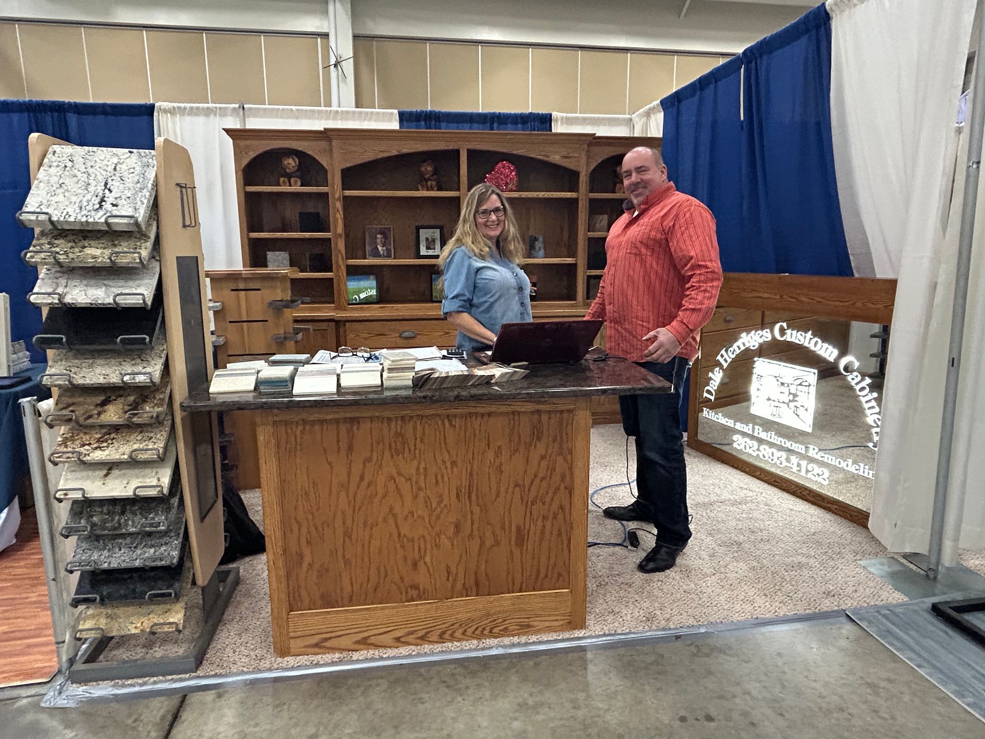 A man and a woman are standing at a counter in a room.