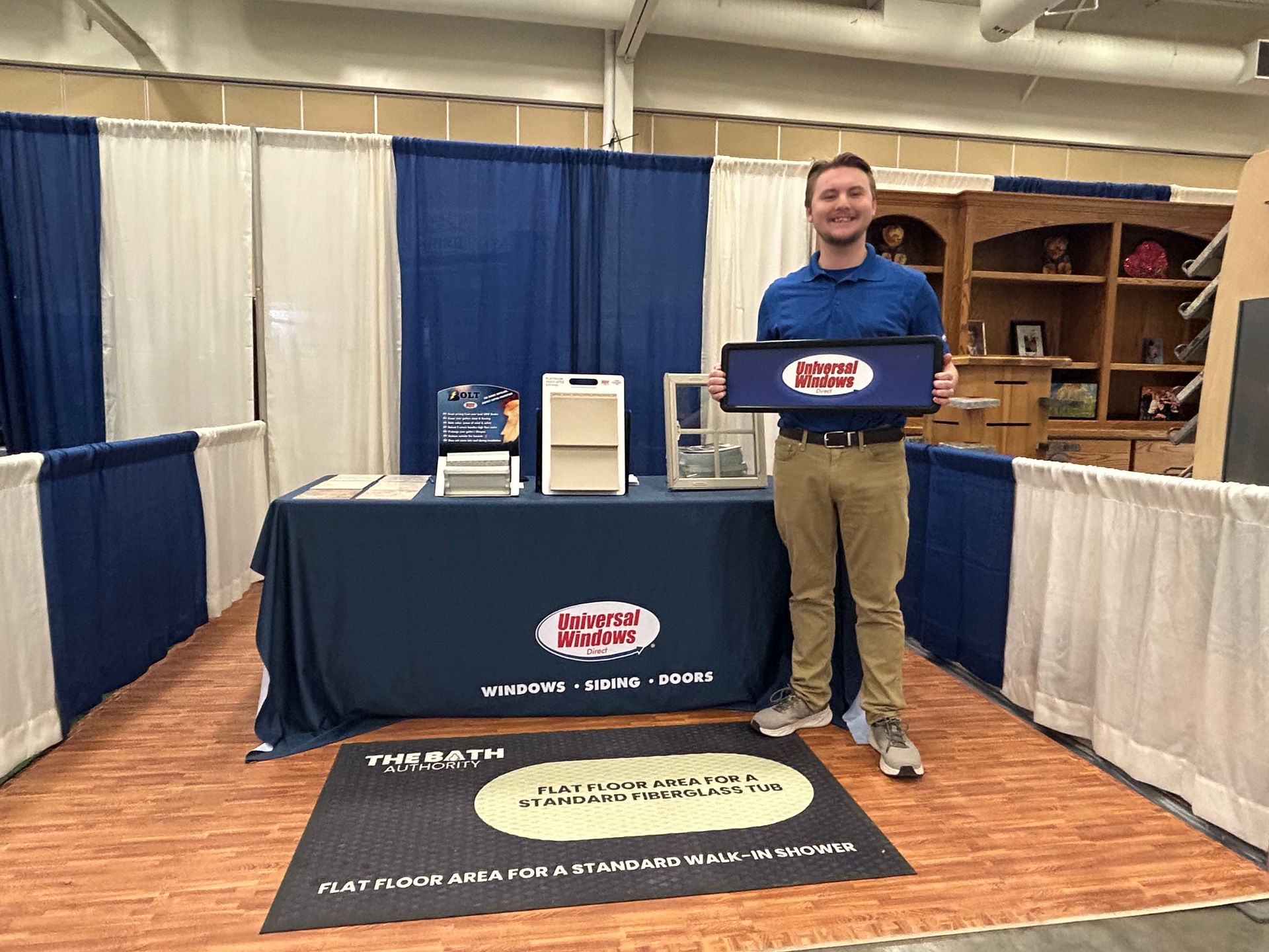 A man is standing in front of a table holding a sign.