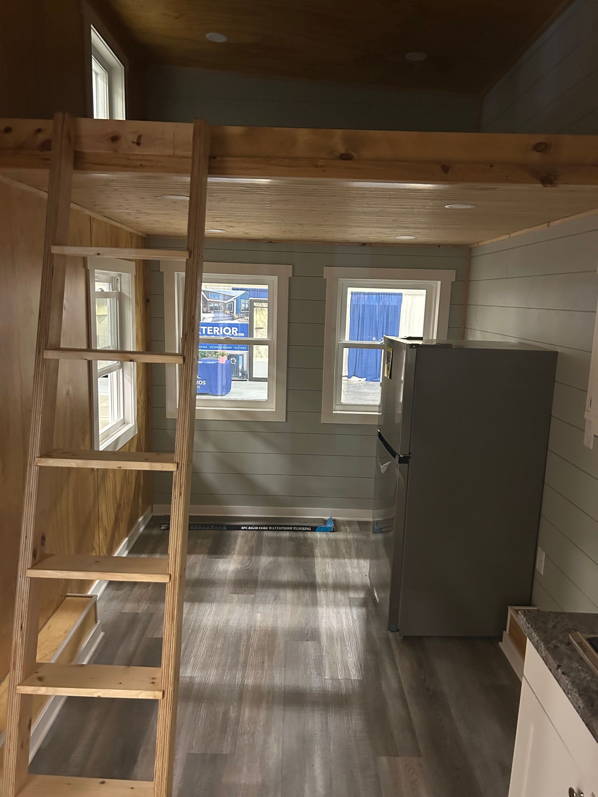 A room with a ladder and a refrigerator in it