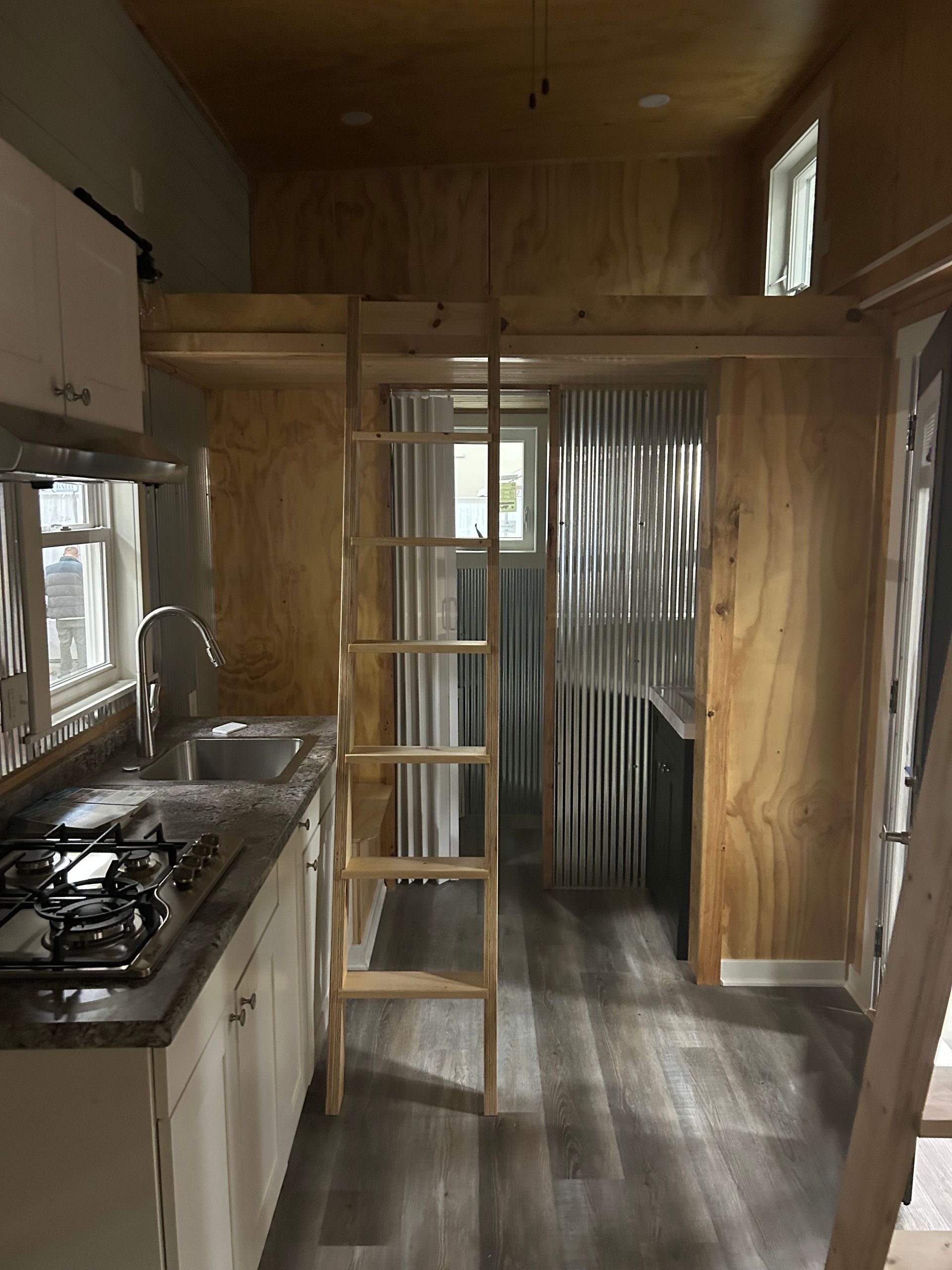 A kitchen in a small house with a ladder leading up to the second floor.