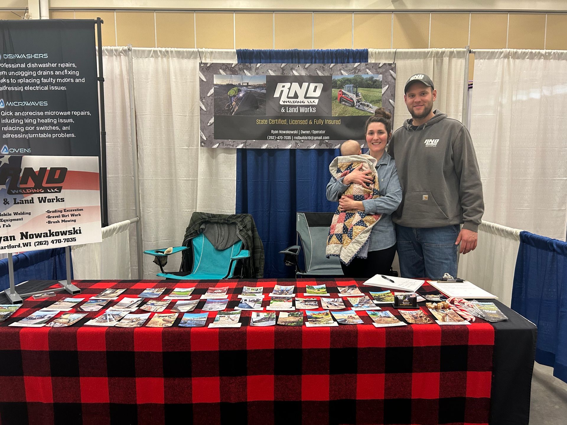 A man and a woman are standing in front of a table holding a baby.