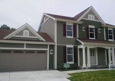 A large green house with a brown garage door