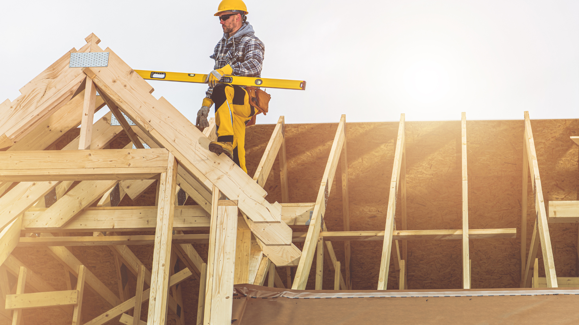 A construction worker is standing on top of a wooden structure.