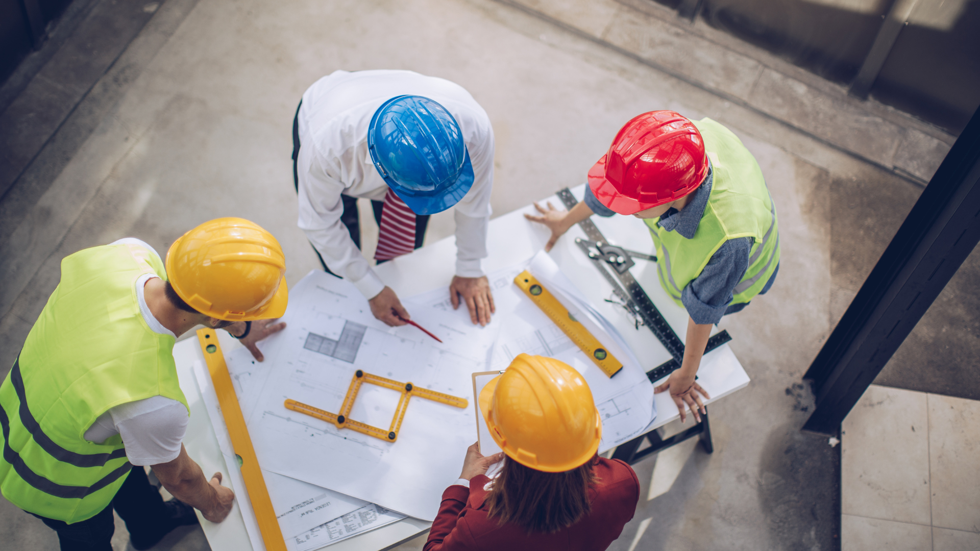 A group of construction workers are sitting around a table looking at a blueprint.