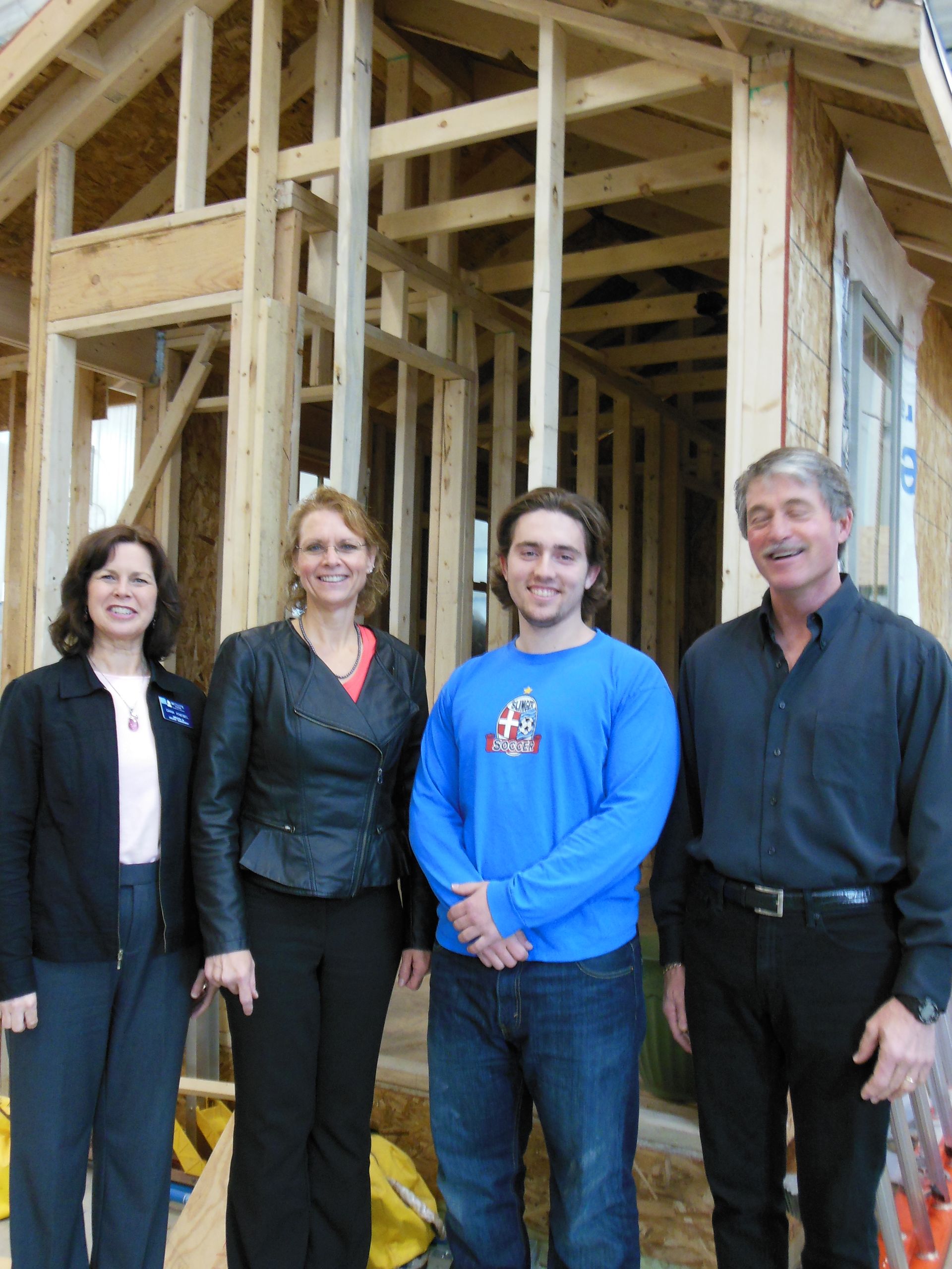 A group of people standing in front of a house under construction