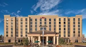Hotel exterior with pool and lounge chairs. Blue sky overhead.