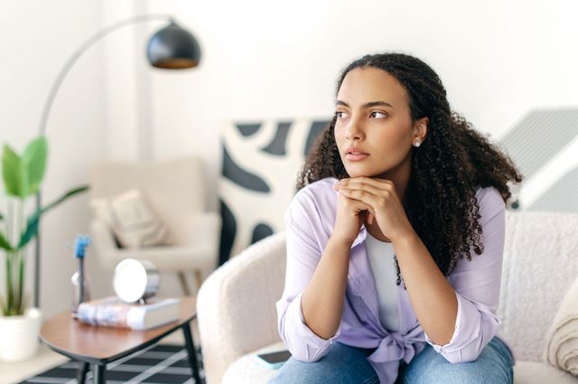 A woman sitting on couch with face on her hands.