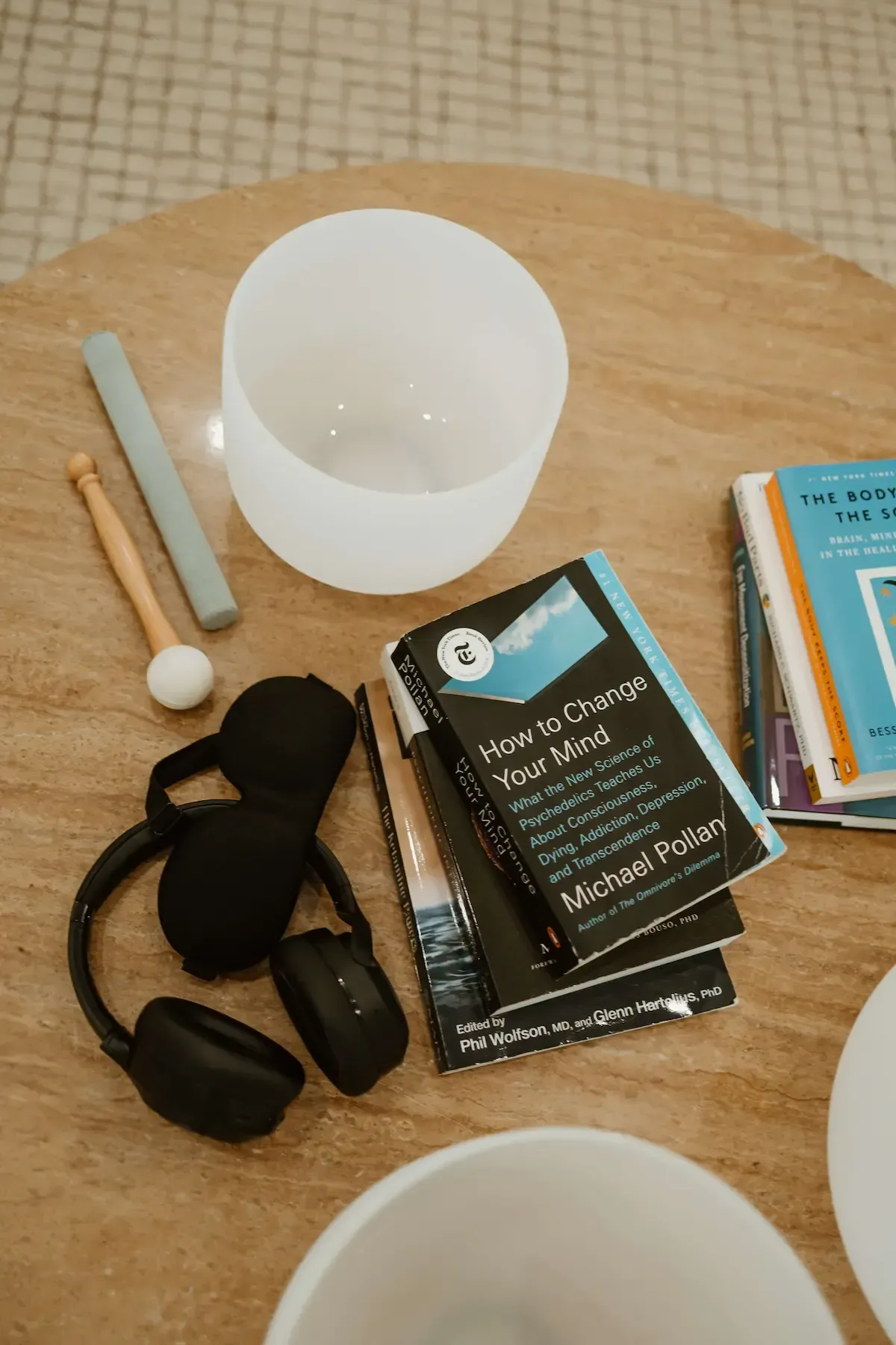 Ketamine therapy headphones and books with crystal sound bowls on a table in preparation for a ketamine therapy session.