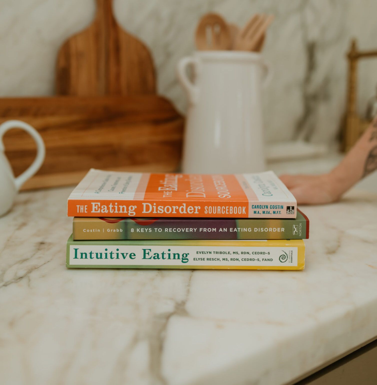 Stack of eating disorder recovery books on a marble countertop at a Houston eating disorder therapy