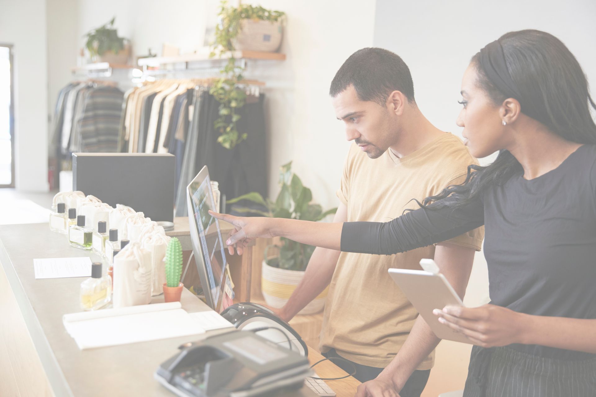 A man and woman retail employees looking at POS systems in fashion store. Image is for retail staffing