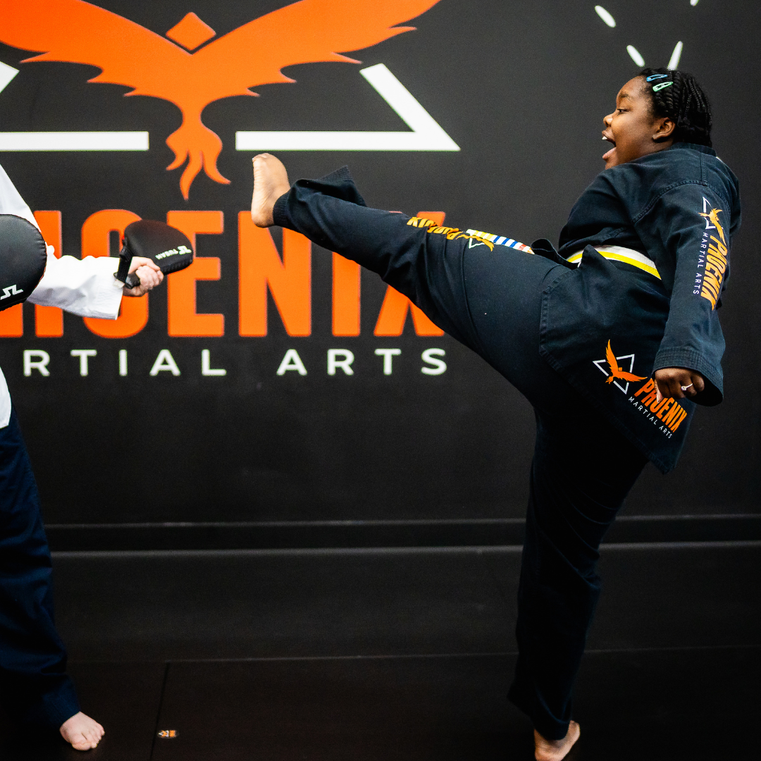 Adult martial arts student performing a roundhouse kick on a target at Phoenix Martial Arts in Murfreesboro, TN