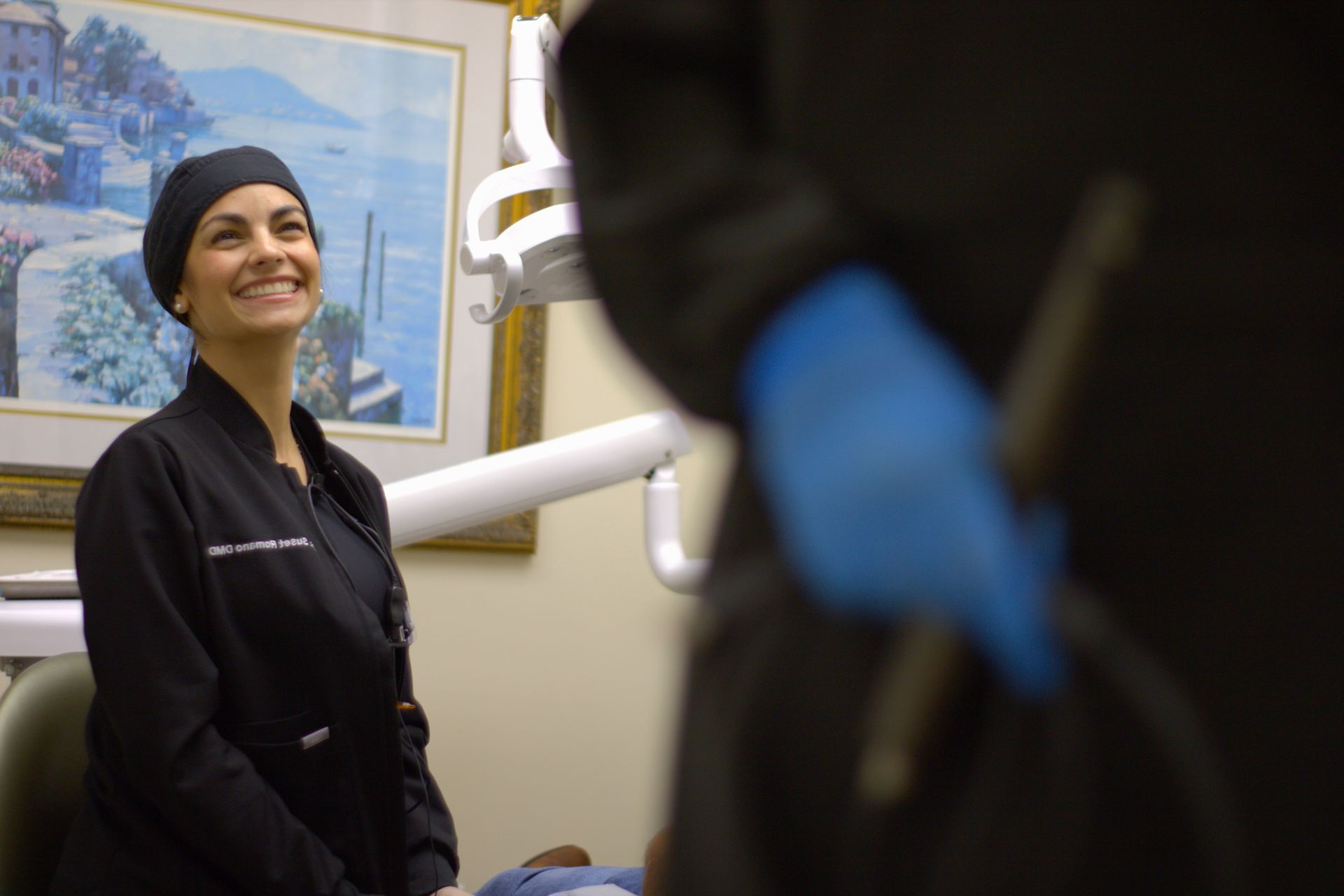 Group of dental office staff in black scrubs, posing in front of a framed painting.