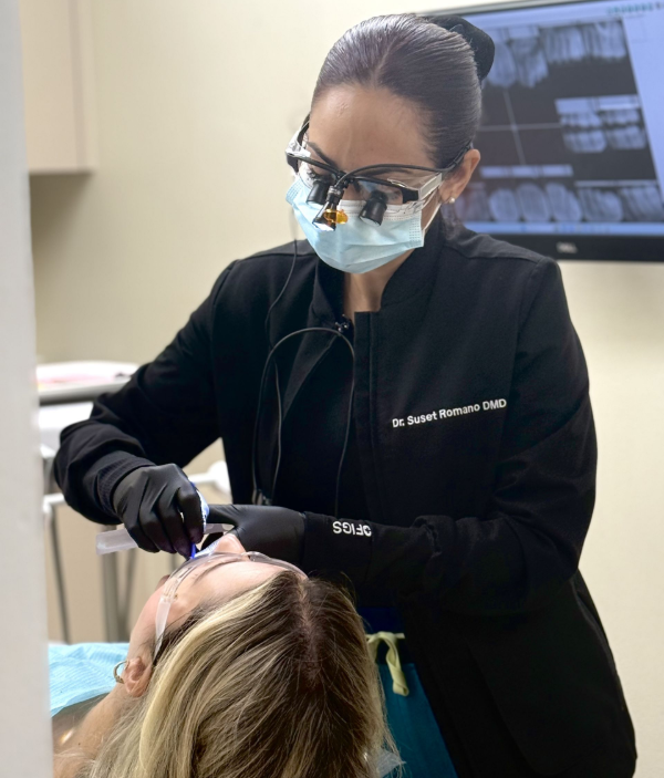Un dentista, con mascarilla y guantes, examina a un paciente en el sillón dental utilizando sus instrumentos en una clínica.