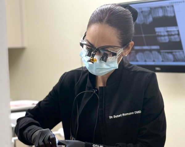 Dentist in black scrubs and mask examining X-rays in a clinic