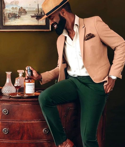 a man sitting on a dresser holding a bottle of whiskey
