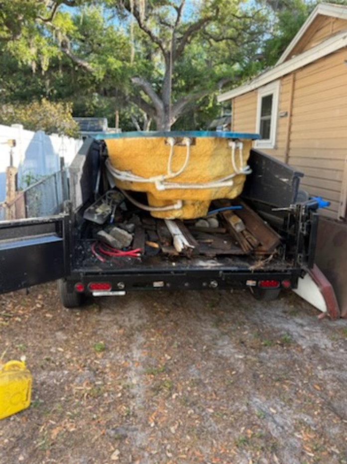 A dump trailer filled with construction debris, including wood planks, trim, and scrap building materials.