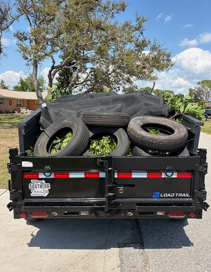A person dressed in black stands by the back of a truck, loading or organizing various boxes, bags, and items.