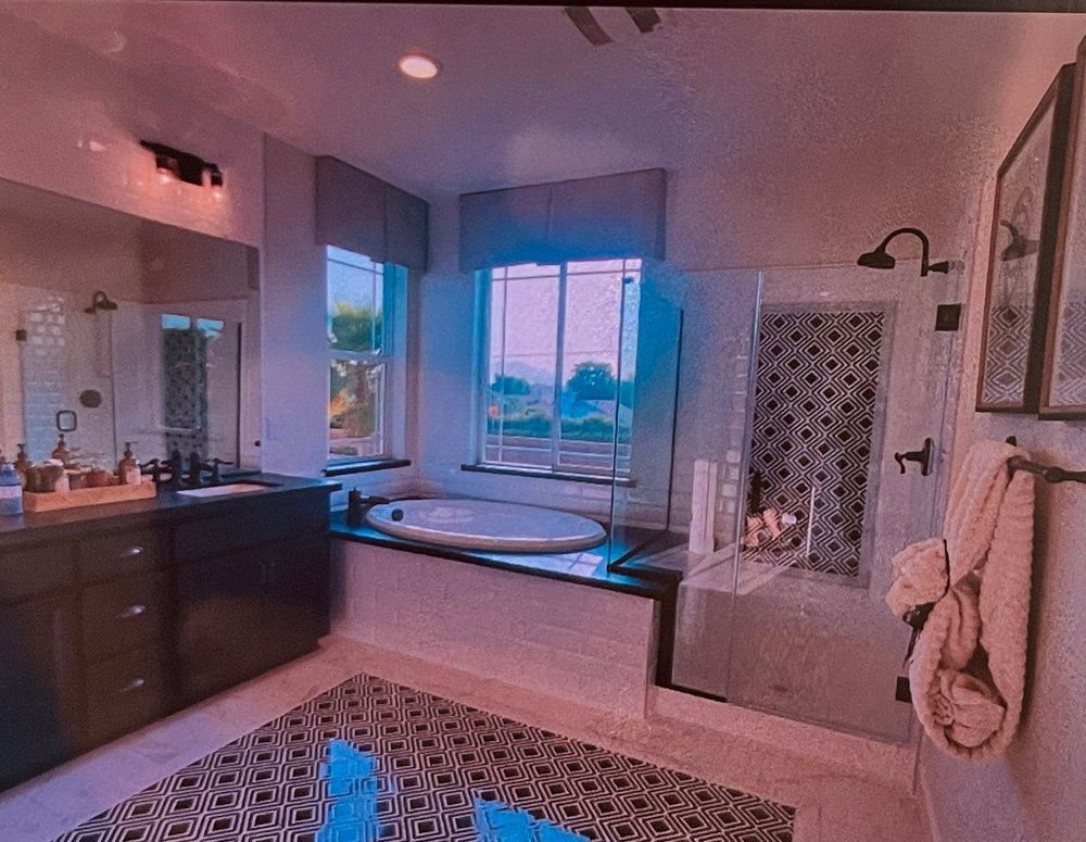 Bathroom with soaking tub, glass shower, black vanity, patterned rug, window with a view.