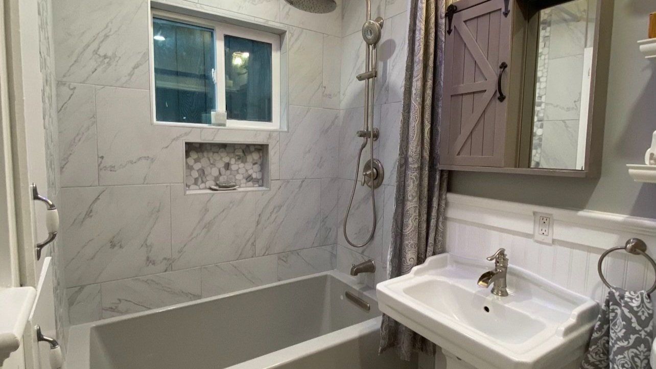 Bathroom with marble tile, a bathtub, and a farmhouse-style vanity.