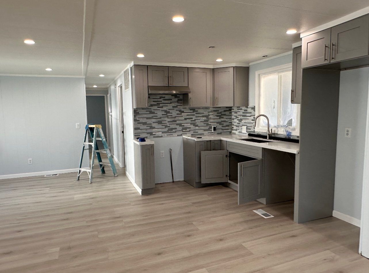Newly renovated kitchen with gray cabinets, a mosaic backsplash, and light wood flooring.
