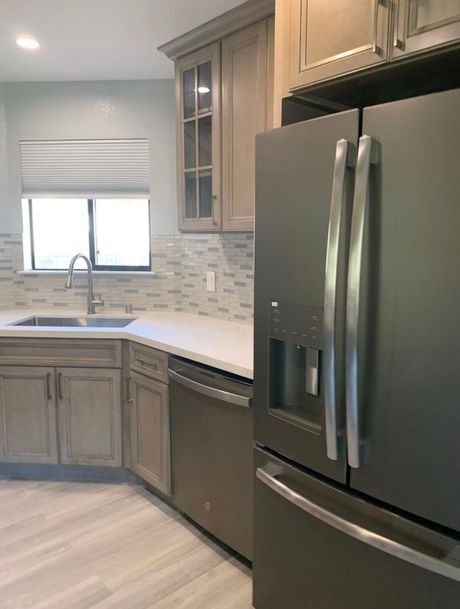 Kitchen with gray cabinets, stainless steel appliances, and a window with a blind.