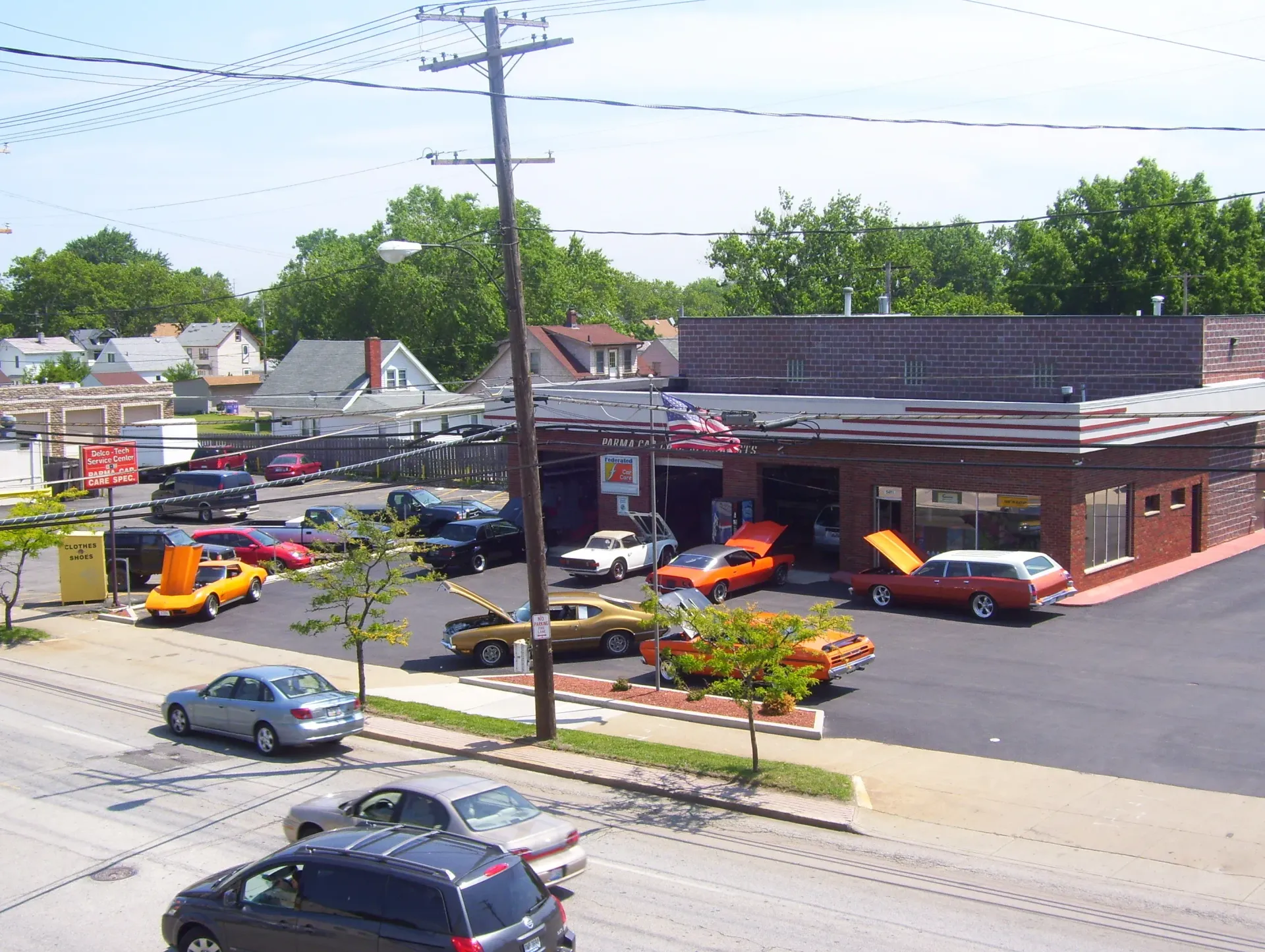 Auto repair shop with several orange cars parked outside on a sunny street corner
