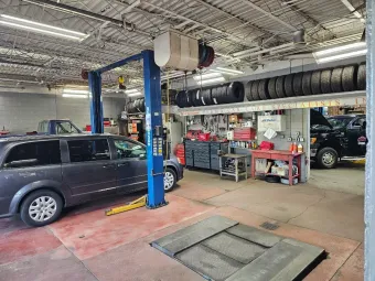 Auto repair shop interior with cars on lifts, tool bench, and open service bay