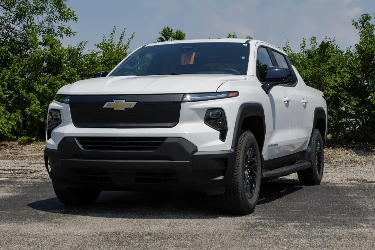 White Chevrolet pickup truck parked outdoors on a gravel lot with trees in the background