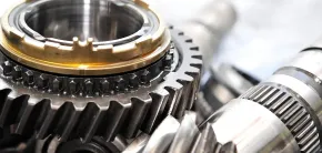 Close-up of shiny metal gears and bearings in a mechanical assembly, with a gold ring detail.