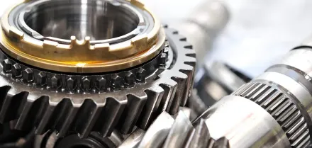 Close-up of shiny metal gears and bearings in a mechanical assembly, with a gold ring detail.