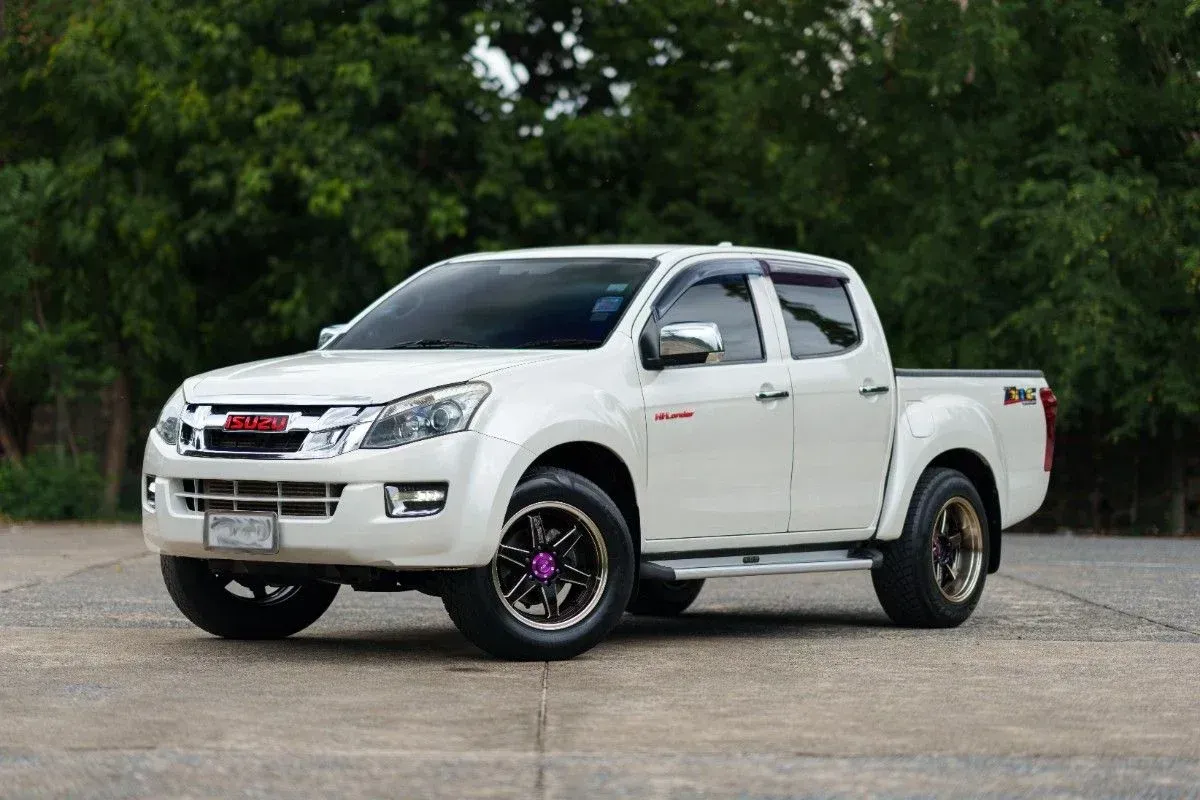 White pickup truck parked on pavement, side view, with trees in the background