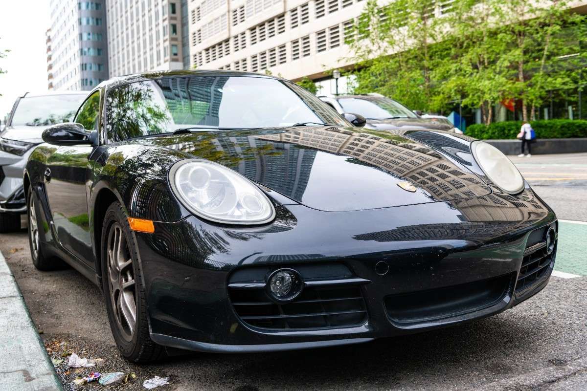 Black Porsche sports car parked on a city street with tall buildings in the background