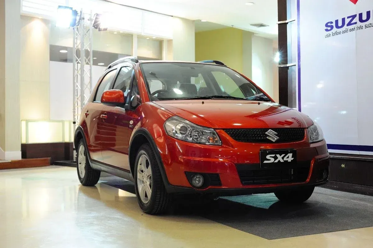 Red Suzuki SX4 displayed indoors in a showroom