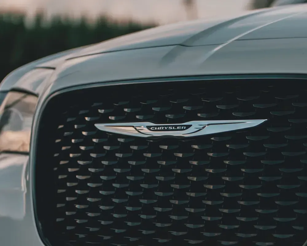 Close-up of a silver Chrysler grille and winged emblem on a black front fascia