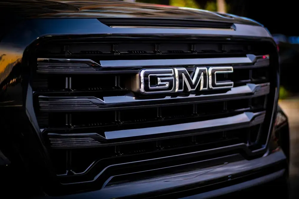 Close-up of a black GMC truck grille with chrome logo and blue-tinted headlights