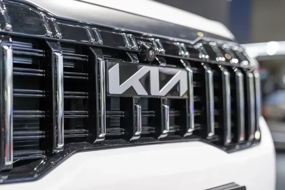 Close-up of a Kia car grille with chrome accents and the KIA logo on a white vehicle