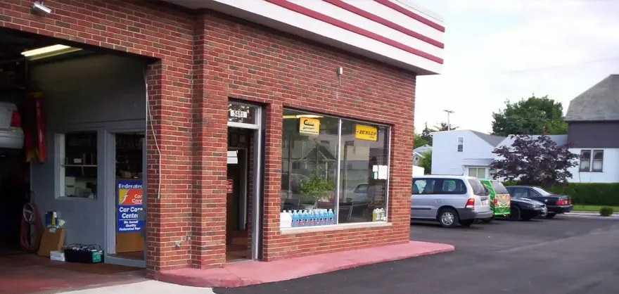 Corner brick convenience store with striped awning and parked cars outside