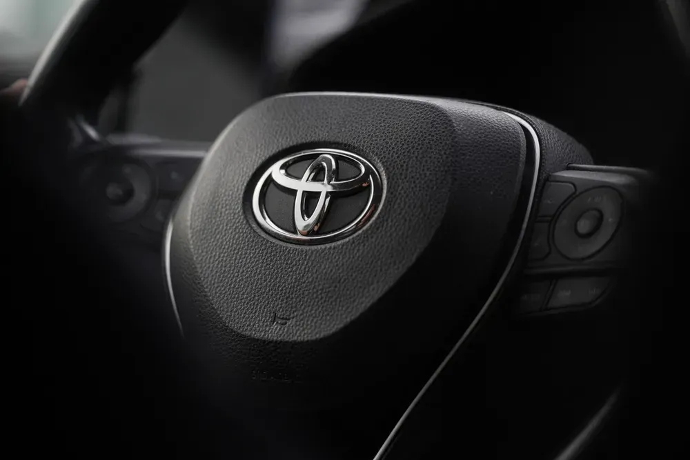 Close-up of a Toyota steering wheel with logo in a dark car interior