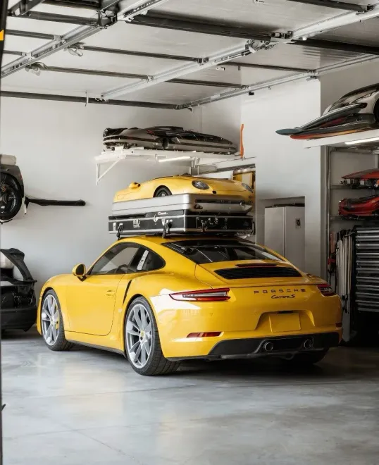 Yellow sports car parked in a modern garage with cars stacked on wall-mounted racks.