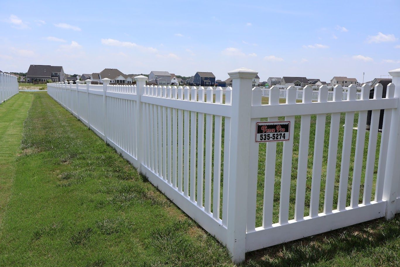 A white picket fence is sitting in the middle of a lush green field.