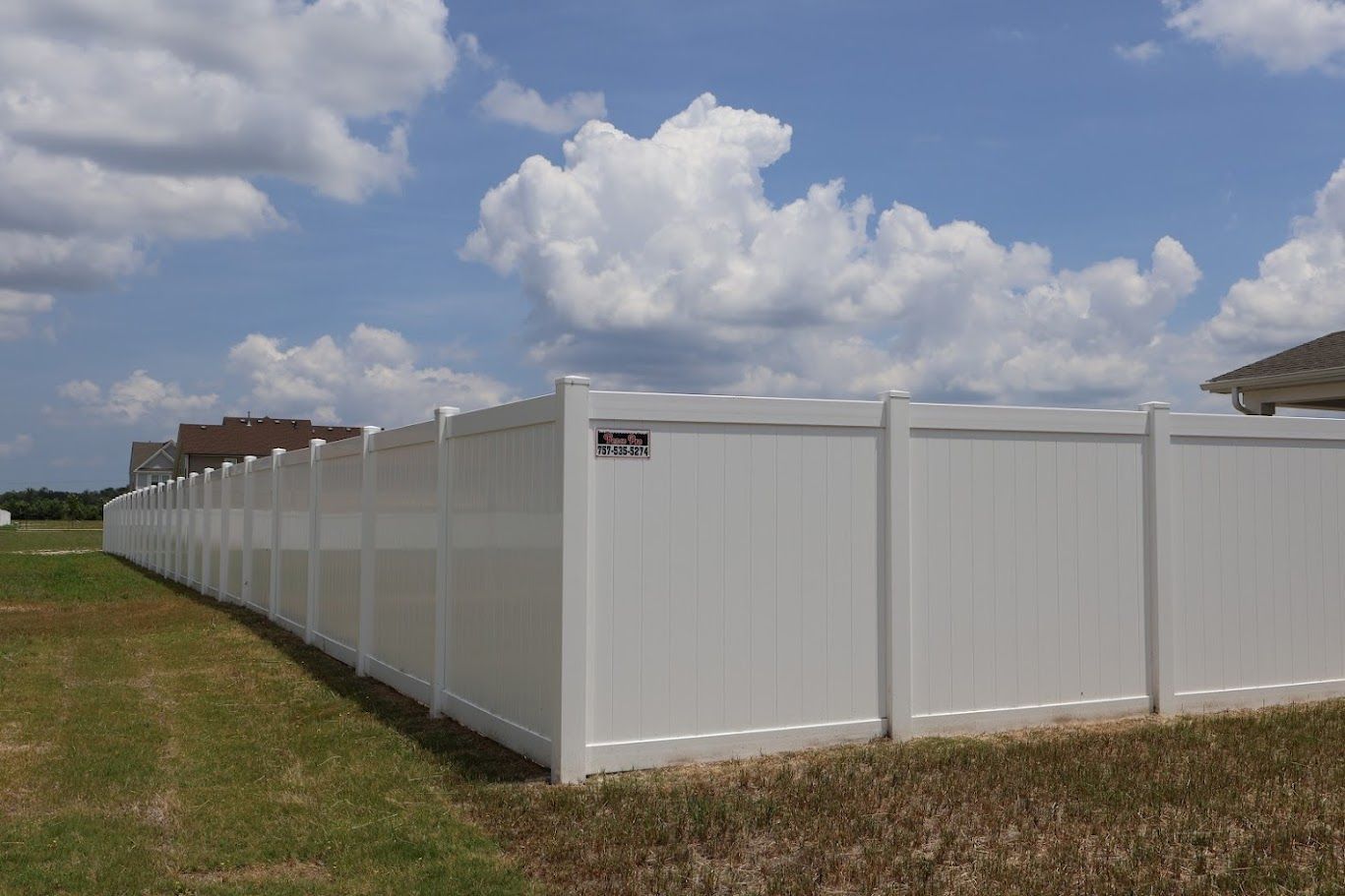 A long white fence is sitting in the middle of a grassy field.