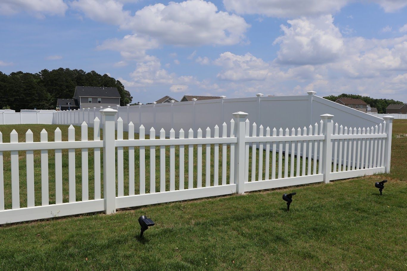 A white picket fence surrounds a lush green field