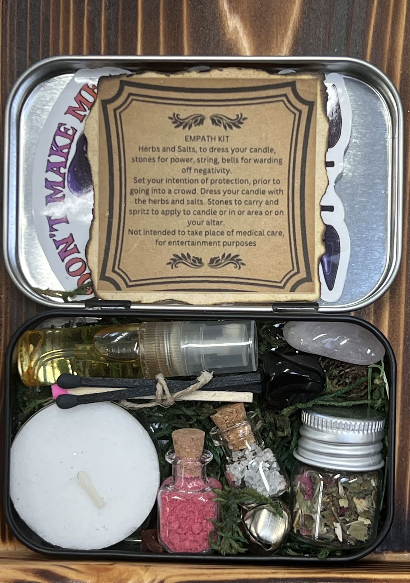 A tin filled with bottles , a candle , and a book.