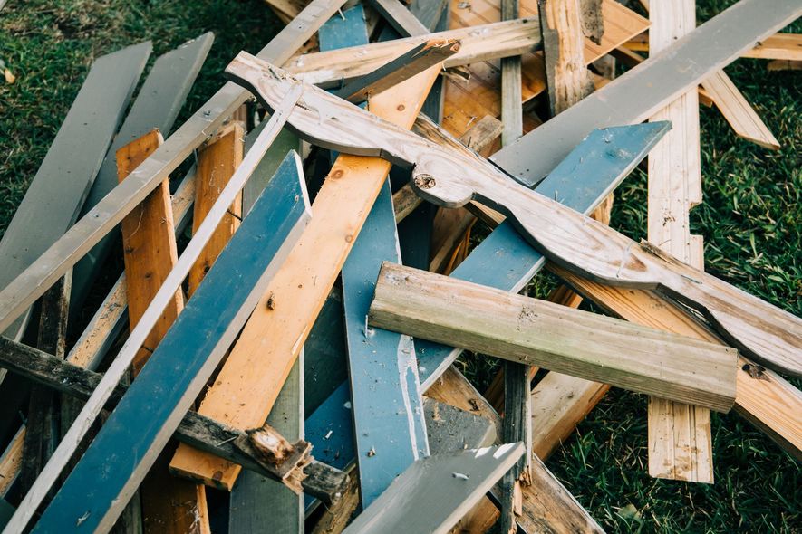 Pile of broken wooden planks and metal scrap on grass