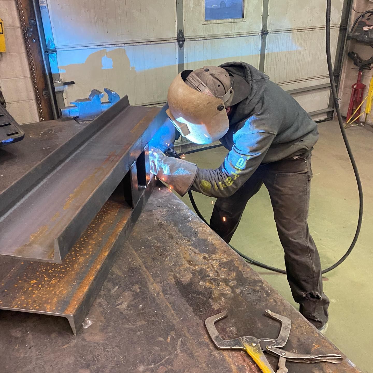 A man is welding a piece of metal in a garage.