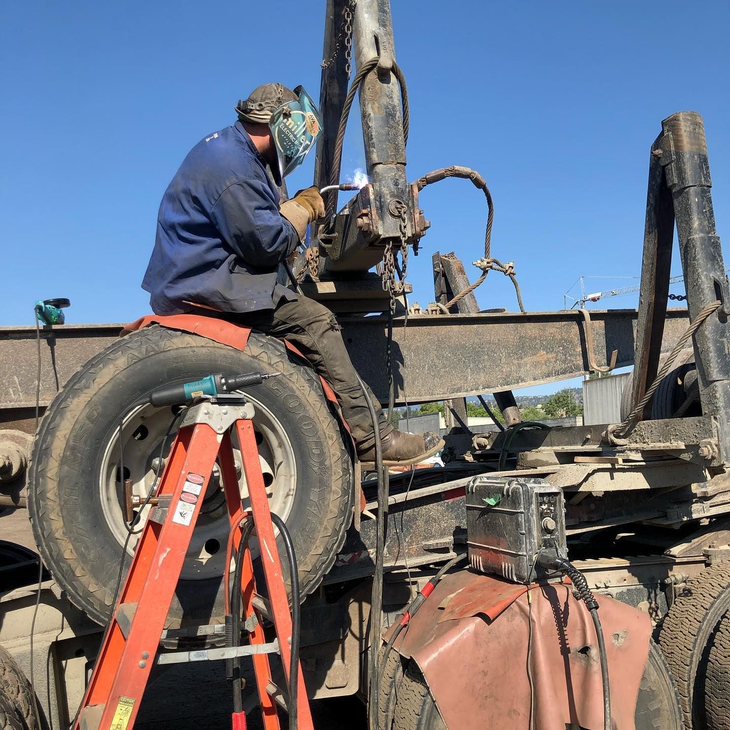 A man is sitting on a ladder working on a truck