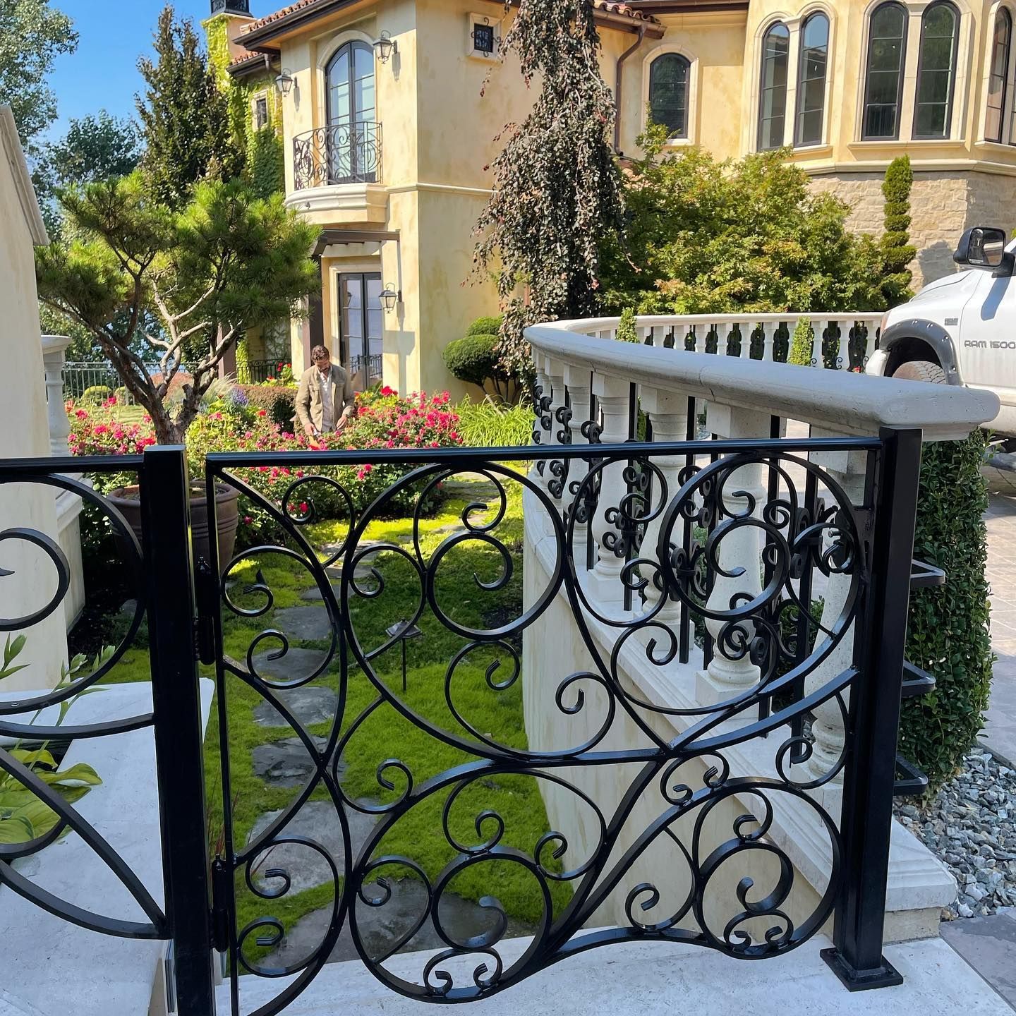 A wrought iron gate is in front of a large house.